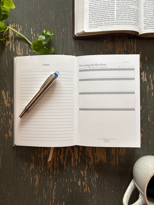 Open FaithBase Journal on a wooden table showing guided reflection pages.